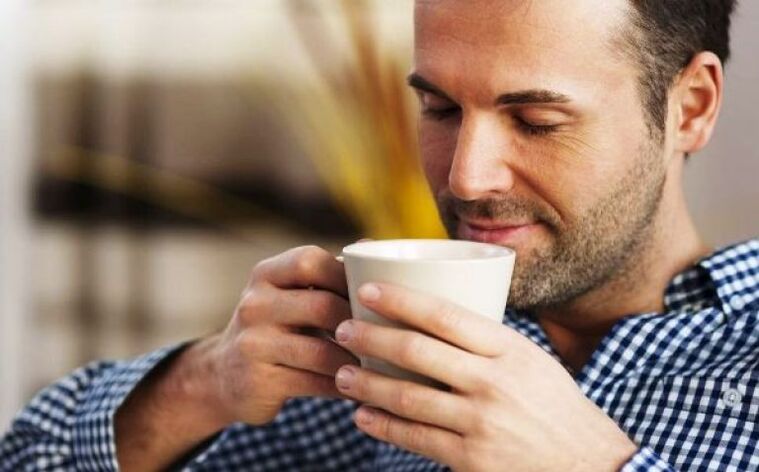 Një burrë pi një pije me çaj drithi për të rritur fuqinë